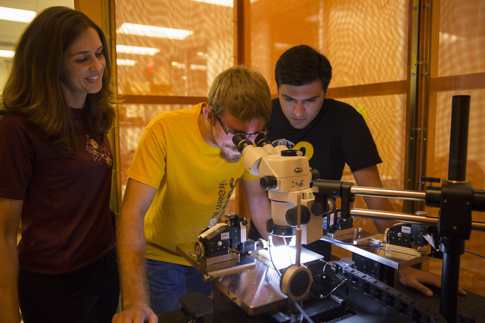 ASU Prof. Jennifer Kitchen with two young male students, one looking through microscope